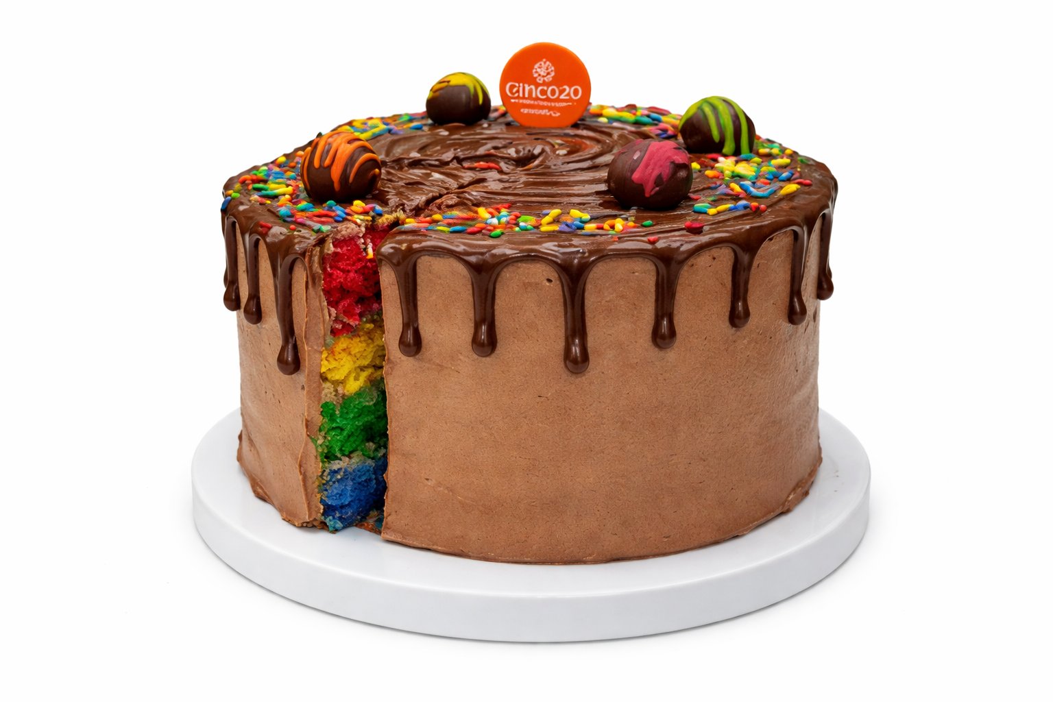 Chocolate layer cake with chocolate drip, candy toppers, and colorful stripe design on white plate