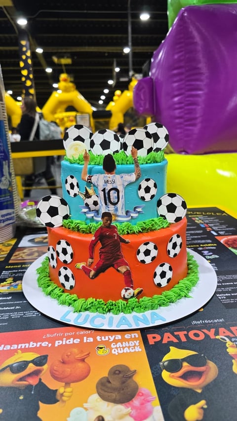 Three-tiered soccer-themed birthday cake with fondant soccer balls, Messi jersey, and player figure in an inflatable play center.