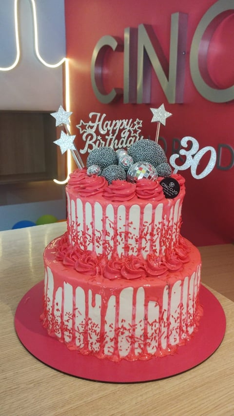 Two-tier pink and white drip cake with Happy Birthday topper, star decorations, and disco ball accents for a 30th birthday celebration